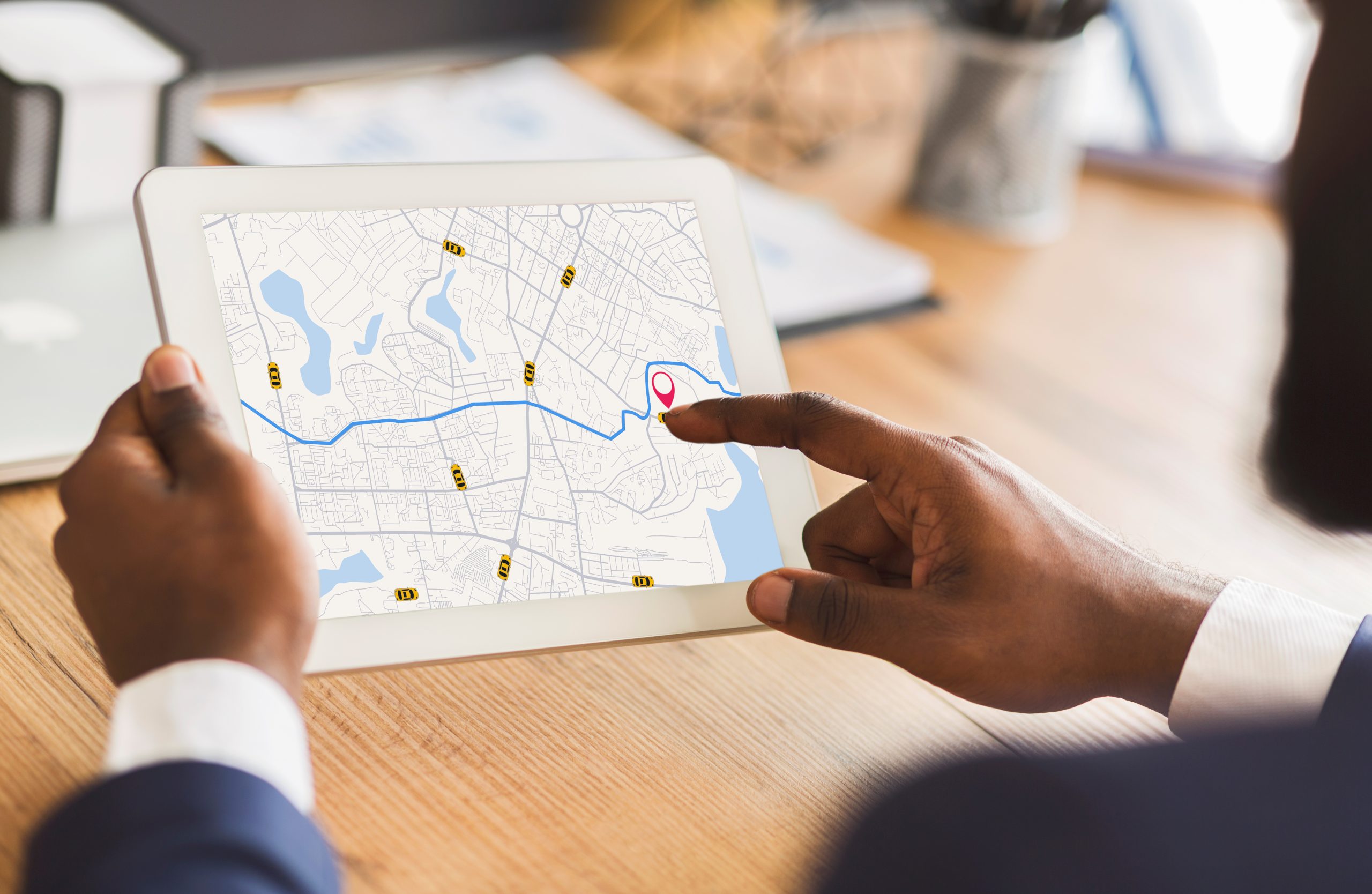 Homem de negócios negro irreconhecível usando aplicativo de serviços de táxi em tablet digital no escritório, olhando o mapa virtual com rastreadores GPS, verificando o táxi mais próximo, colagem criativa para conceito de transporte