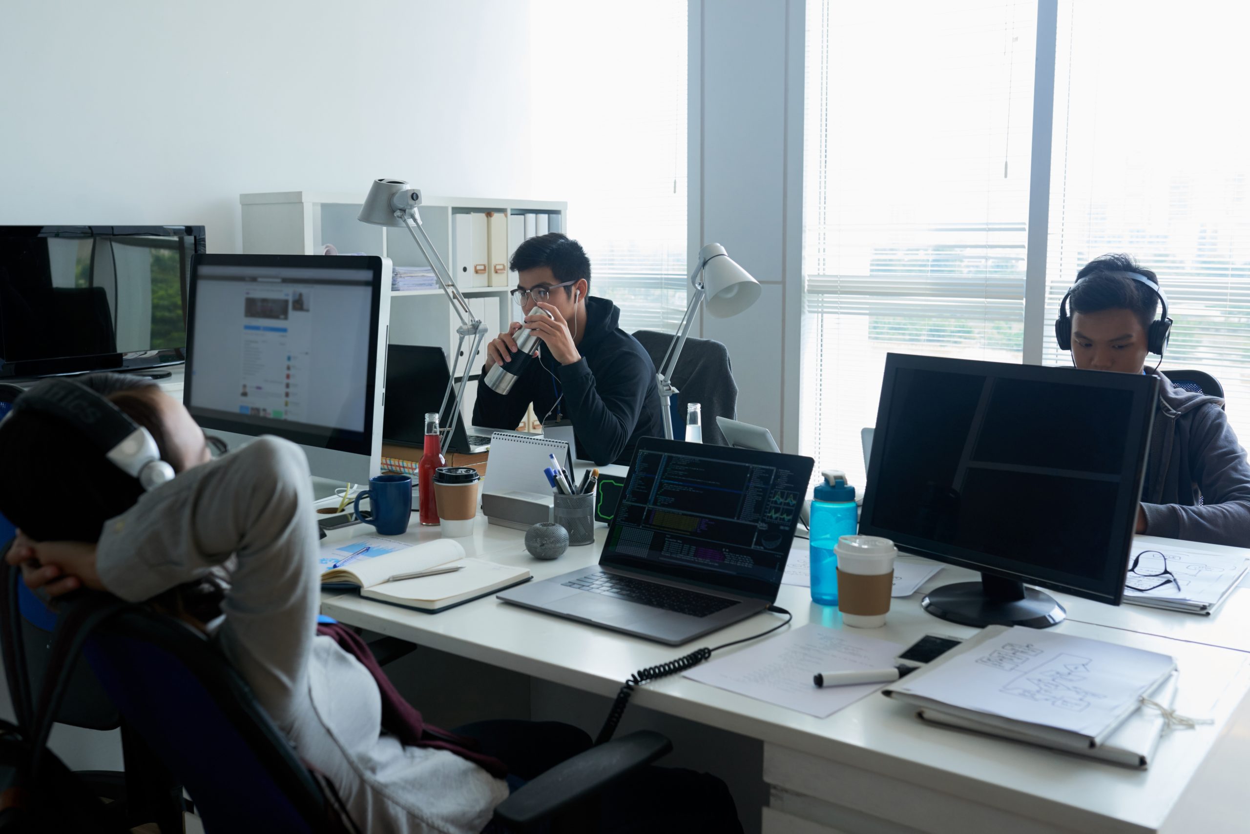 Equipe de jovens programadores asiáticos trabalhando em um escritório de espaço aberto